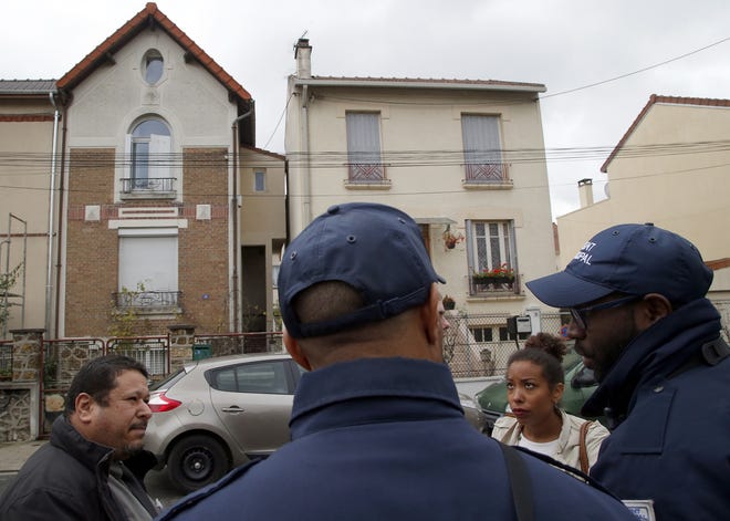 Residents talk on Tuesday to police officers guarding a house, left, where one of the Paris attackers supposedly stayed, in Bobigny, near Paris, France. AP/Michel Euler