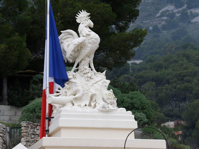 A French flag flies at half-mast by a symbol for France, the Gallic rooster, on the top of a war memorial in a cemetery in tribute to the victims of last Friday's attacks in Paris, in Beausoleil, near Menton, southeastern France, Tuesday, Nov. 17, 2015.