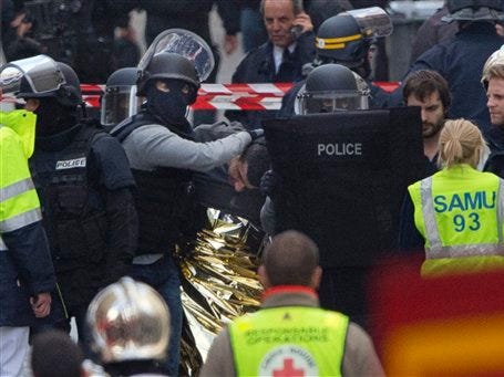 Hooded police officers detain a man in Saint-Denis, near Paris, Wednesday, Nov. 18, 2015. A woman wearing an explosive suicide vest blew herself up Wednesday as heavily armed police tried to storm a suburban Paris apartment where the suspected mastermind of last week's attacks was believed to be holed up, police said.