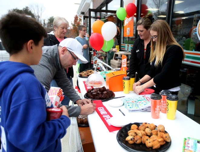 Photo by Jake West/New Jersey Herald - Eddy Hand, of Sparta, enters a raffle to win a new mountain bike as part of a promotional giveaway during the grand opening celebration of the new 7-11 in Sparta, on Saturday, November 7, 2015,. Store manager Jennifer Vorst, second from right, and assistant manager Jade Kostka, far right, operate the giveaway table.