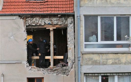 People work inside the damaged building of Wednesday's raid on an apartment in the Paris suburb of Saint-Denis, Thursday Nov.19, 2015. Abdelhamid Abaaoud, the Belgian extremist suspected of masterminding the deadly attacks in Paris died a day ago along with his female cousin in a police raid on a suburban apartment building.(AP Photo/Christophe Ena)