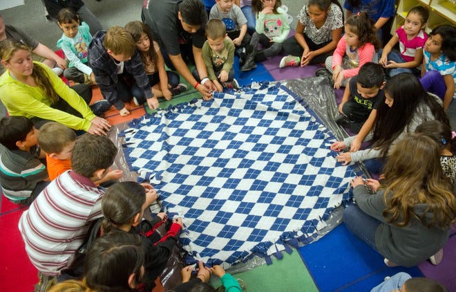A group of fifth graders and kindergarteners work on a blanket Thursday at Shasta Elementary School in Manteca as they craft blalnkets for needy students. CLIFFORD OTO/THE RECORD
