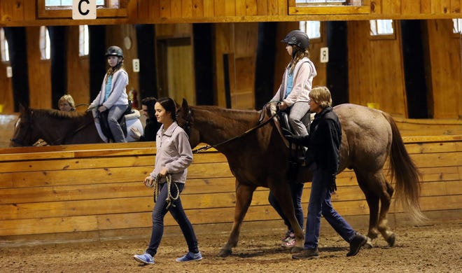 Ten-year-old Sarah Campanello, of Lincoln, rides Sparky, a 15-year-old quarter horse, around the indoor ring at Friends For Tomorrow. Helping her are volunteer Sarah Buschman, left, and instructor Lucy Cornish. In back is volunteer Alyssa Kotelly. Wicked Local Staff Photo/Ann Ringwood