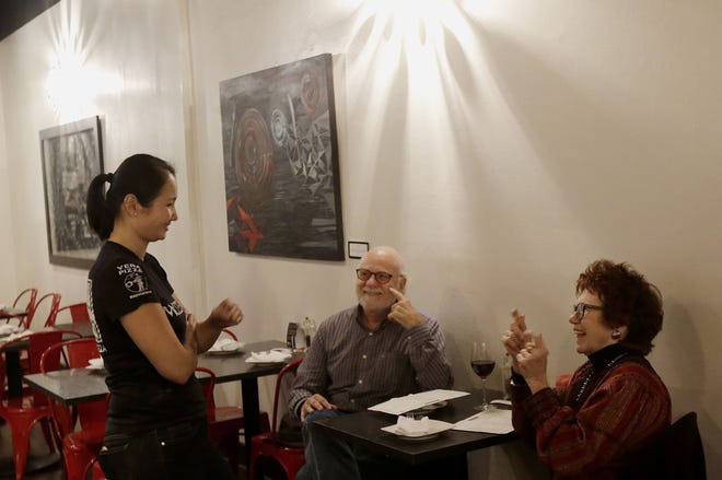 Mozzeria owner Melody Stein, left, communicates Nov. 5 with customers Ronald Ransom and Betty Ann Prinz using sign language in San Francisco. Mozzeria owners Russ and Melody Stein as well as staff workers are deaf and have run their San Francisco restaurant since 2011. Photo/The Associated Press