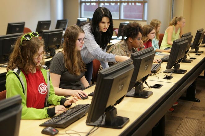 Emily Hennessy, senior computer science major at Florida State University Panama City, helps students create video games during a recent “Girls Who Code” class.
