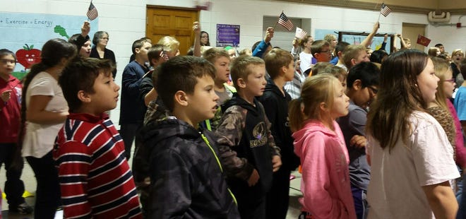 Students wave flags during the assembly. Courtesy Photo