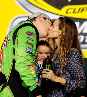 Kyle Busch kisses his wife, Samantha, with their son, Brexton, with them, after winning the NASCAR Sprint Cup Series race and the season title, Sunday. (AP Photo/Terry Renna)