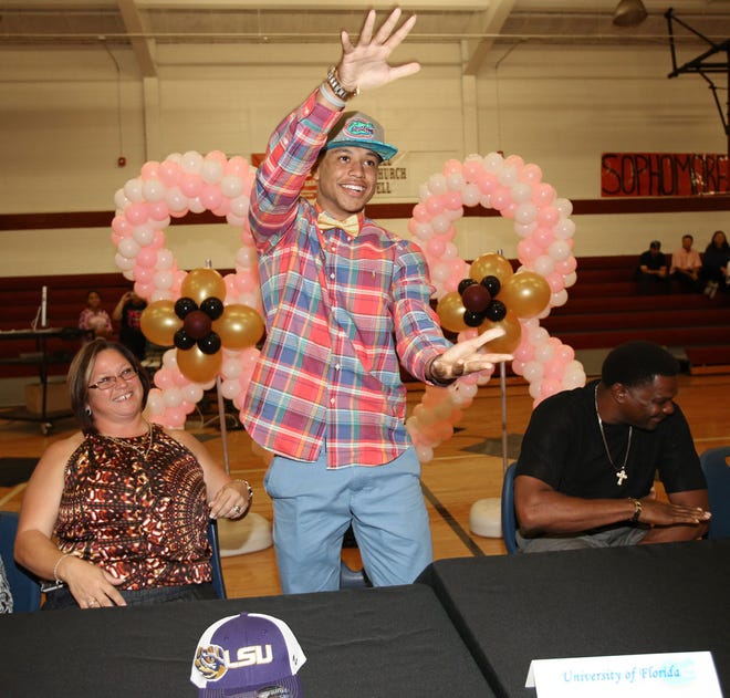 North Marion's Freddie Swain, center, does the Gator chomp, as his parents, Brenda Geromel, left, and his father, John Swain, right, look on during a ceremony where Swain announced that he intends to sign with the University of Florida football program at North Marion High School in Sparr on Oct. 9. Swain, a wide receiver, had football offers from six schools before making his decision to sign with UF.