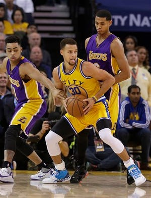 Golden State Warriors guard Stephen Curry (30) is defended by Los Angeles Lakers guards D'Angelo Russell, left, and Jordan Clarkson during the first half of an NBA basketball game in Oakland, Calif., Tuesday, Nov. 24, 2015. (AP Photo/Jeff Chiu)
