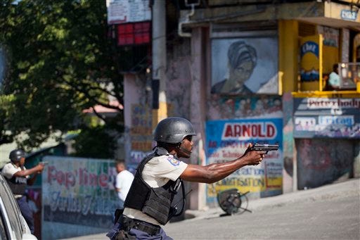 National police officers fire their weapons towards demonstrators during a protest against the official election results, in Port-au-Prince, Haiti, Tuesday, Nov. 24, 2015. Government-backed candidate Jovenel Moise and former state construction chief Jude Celestin, officials said, are the the two top finishers that will compete in a runoff vote on Dec. 27. The announcement by the nine-member Provisional Electoral Council, set off a new wave of protests by supporters of Moise Jean-Charles, one of the leading candidates from a field of 54, that denounced the results. (AP Photo/Dieu Nalio Chery)