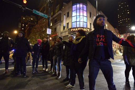 Protesters block a street during a protest for 17-year-old Laquan McDonald, Tuesday, Nov. 24, 2015, in Chicago. Chicago police Officer Jason Van Dyke, who shot McDonald 16 times last year, was charged with first-degree murder Tuesday, hours before the city released a video of the killing.