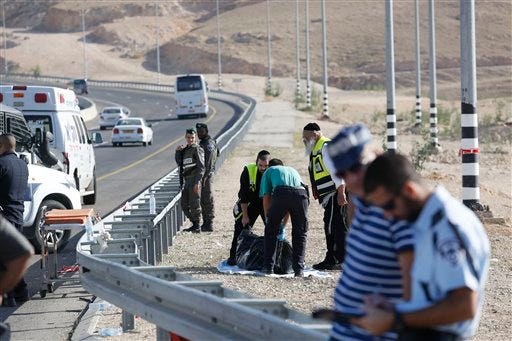Israeli emergency services lift the body of an alleged Palestinian attacker near Kfar Adumim settlement in the West Bank, Friday, Nov 27, 2015. Israeli officials say a Palestinian was shot and killed after ramming his car into a group of Israelis, injuring soldiers in the attack. (AP Photo/ Nasser Shiyoukhi)