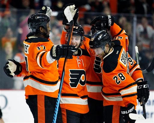 Philadelphia Flyers' Shayne Gostisbehere, center, who scored the game-winning goal is surrounded by teammates, from the left, Wayne Simmonds, Jakub Voracek, rear, and Claude Giroux as they celebrate the end of overtime period of an NHL hockey game against the Nashville Predators Friday, Nov. 27, 2015 in Philadelphia. The Flyers won 3-2. (AP Photo/Tom Mihalek)