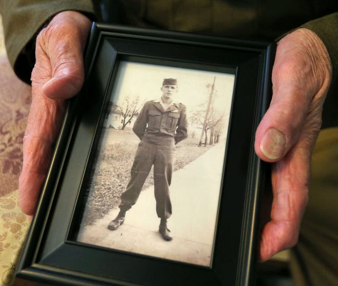 Peter Wasmiller holds a photo of himself from his time in the military.