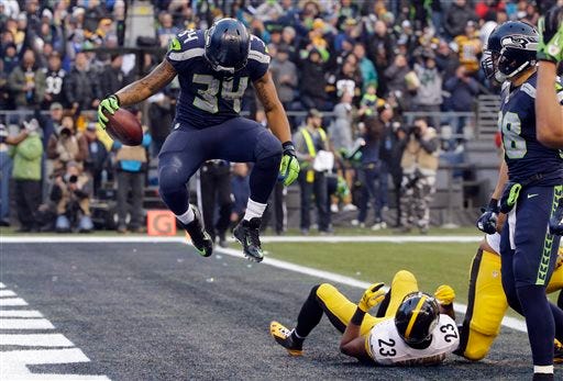 Seattle Seahawks' Thomas Rawls (34) jumps after scoring a touchdown as Pittsburgh Steelers' Mike Mitchell lies in the end zone in the second half of an NFL football game, Sunday, Nov. 29, 2015, in Seattle. (AP Photo/Ted S. Warren)
