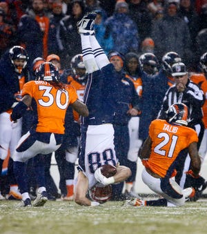 Patriots tight end Scott Chandler is flipped over by Broncos cornerback Aqib Talib, right, and safety David Bruton during the second half Sunday. The Associated Press