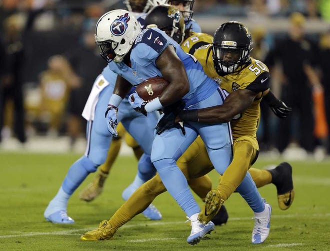 Tennessee Titans running back Antonio Andrews (26) is stopped by Jacksonville Jaguars outside linebacker Telvin Smith (50) during the first quarter of an NFL football game Thursday, Nov. 19, 2015, in Jacksonville, Fla. (AP Photo/Chris O'Meara)