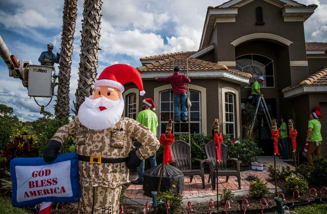 Florida Power and Light employees help decorate of the home of Florida Army National Guard Corteney Callis on Tuesday. Callis was deployed for eight months last year, and was home only briefly for Christmass. STAFF PHOTO / NICK ADAMS