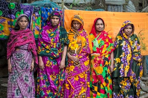 In this Nov. 18, 2015 photo, women who lost their homes to the River Meghna stand for a photograph at a government shelter in the island district of Bhola, where the Meghna River spills into the Bay of Bengal, Bangladesh. Though Prime Minister Sheikh Hasina has been internationally recognized for raising awareness of climate-change issues, Bangladesh has no specific plan for dealing with its own people displaced by climate-related disasters, other than offering them temporary shelter. (AP Photo/Shahria Sharmin)