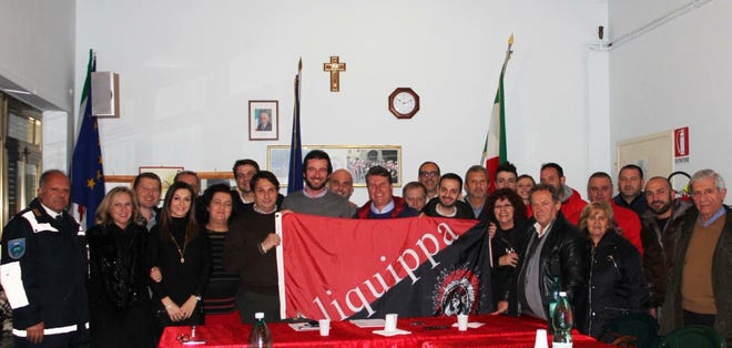 Patrica, Italy's mayor, Lucio Fiordalisio, is shown behind an Aliquippa flag with others in their community as Patrica officials approved a sister-city relationship with Aliquippa. Also shown is Aldo Conti, the president of a tourism outreach called Pro-Loco Patrica. Conti spearheaded efforts for the sister-city relationship.