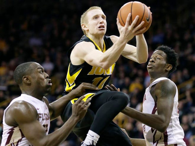 Iowa guard Mike Gesell, center, drives to the basket between Florida State's Montay Brandon, left, and Jarquez Smith, right, during the second half of an NCAA college basketball game, Wednesday, Dec. 2, 2015, in Iowa City, Iowa. Iowa won 78-75 in overtime.