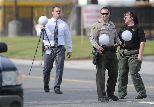 San Bernardino County Sheriff's officials conduct the investigation on Thursday Dec. 3, 2015, at the scene of the shoot out between law enforcement officers and suspects in a mass shooting on Orange Show Drive in San Bernardino, Calif. A heavily armed husband and wife dressed for battle opened fire on a holiday banquet for his co-workers Wednesday, killing multiple people and seriously wounding others in a precision assault, authorities said. Hours later, they died in a shootout with police. (James Quigg/Daily Press via AP)