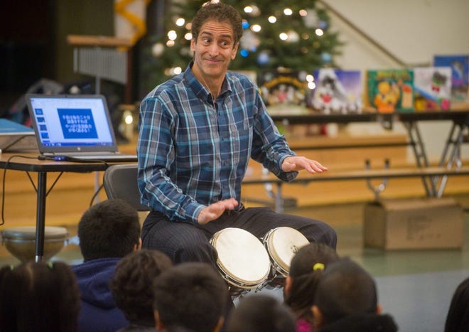 Children's author Matthew Gollub plays bongo drums during a Friday assembly at Spanos Elementary School in Stockton. CLIFFORD OTO/THE RECORD