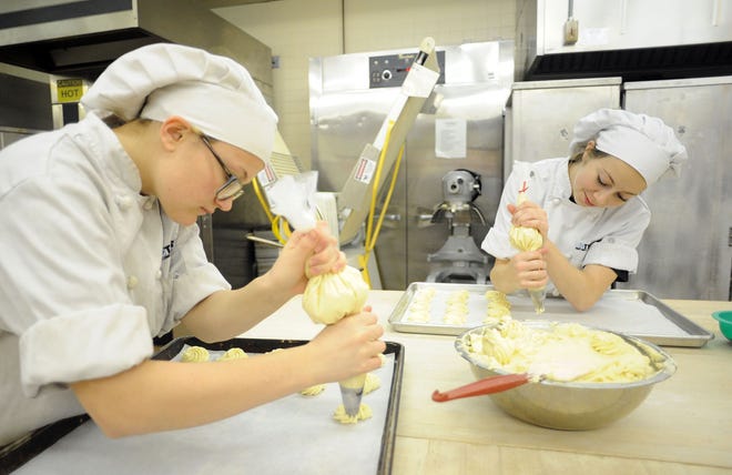 Bucks County Technical School students (from left) Bailey Pellegrino, 18, of Levittown, and Melissa Zavalick, 18 of Yardley, place cookie dough on a tray Friday Dec. 4, 2015, in preparation for the Christmas sale at school in Bristol Township.
