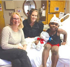Joi Akridge and Paula Frances Price, Junior League volunteers, visit with pediatrics patient Isaiah Hood