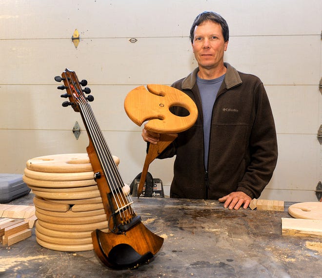 Woodworker Kerry Pudenz displays wooden wine tables made from white oak that hold a bottle of wine and wine glasses and can be stuck in the ground. He also made a seven-string electric violin from spruce and cedar.