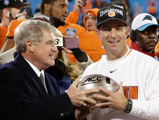 Clemson coach Dabo Swinney, right, accepts the championsip trophy from ACC Commissioner John Swofford after Clemson defeated North Carolina in the Atlantic Coast Conference championship NCAA college football game in Charlotte, N.C., Sunday, Dec. 6, 2015. Clemson won 45-37.
