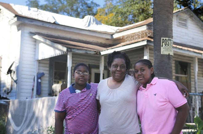 Yolanda Kilow stands with her two sons, Elton Rumph Jr., right, and Treyvon Rumph, in front of her home on Sunday. Yolanda's home is in need of repairs, especially to the roof. (Heather Leiphart | The News Herald)