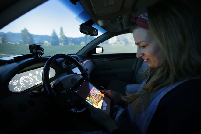 On instructions from Stanford University researchers, Stephanie Balters, of Krefeld, Germany, and the Norwegian University of Science and Technology, watches a video on a tablet rather than monitor the actions of a self-driving car.