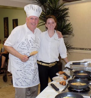 Village on the Isle CEO Tom Kelly poses with Ashley Hodges, Server and Backup Manager with the Hibiscus Dining Room, as omelets cook. COURTESY PHOTO
