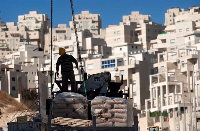Associated Press file photoA worker stands by construction materials in November 2011 to unload at a new housing unit in the east Jerusalem neighborhood of Har Homa.