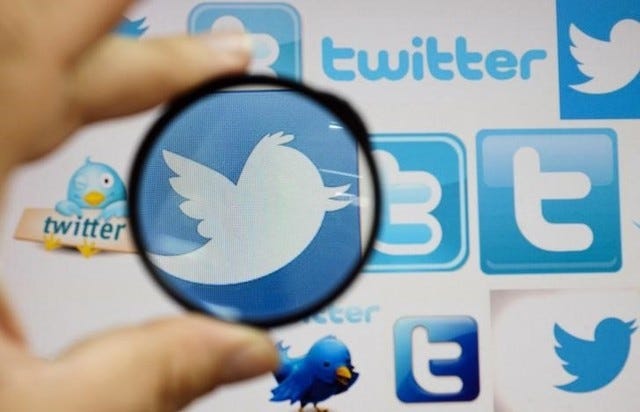 A person holds a magnifying glass over a computer screen displaying Twitter logos, in this picture illustration taken in Skopje September 10, 2013. REUTERS/Ognen Teofilovski