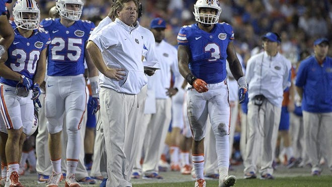 Florida head coach Jim McElwain, center, watches as quarterback Treon Harris (3) walks onto the field during a timeout in the first half of an NCAA college football game against Florida State in Gainesville, Fla., Saturday, Nov. 28, 2015. (AP Photo/Phelan M. Ebenhack)