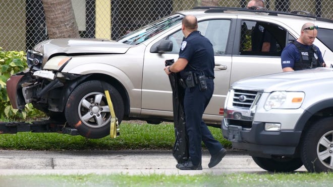 West Palm Beach police investigate a shooting that began with a woman shot on 8th Street and ended up with an SUV crashed in Gaines Park and the driver taken to the hospital with gunshot wounds. (Lannis Waters / The Palm Beach Post)