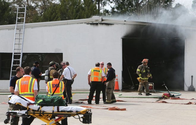 Firefighters and paramedics work the scene of a fire at Emerald Coast Striping in March.