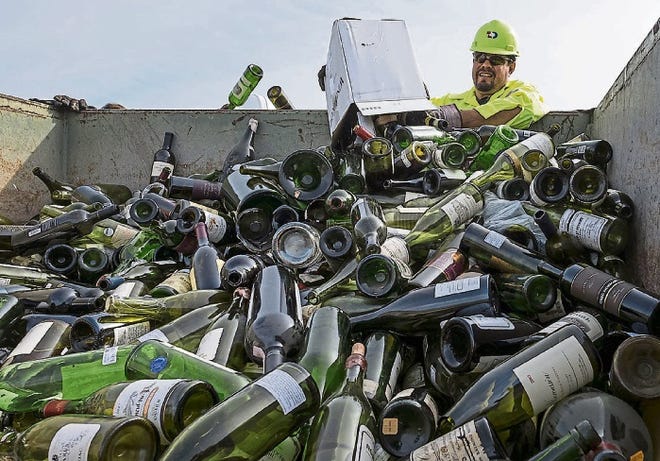 Isidoro Guerra of Texas Disposal Systems in Austin dumps a case of wine into a trash bin to be destroyed. Deputy U.S. marshals destroyed 500 bottles of counterfeit wine passed off as rare vintages by Rudy Kurniawan, who was convicted of fraud.