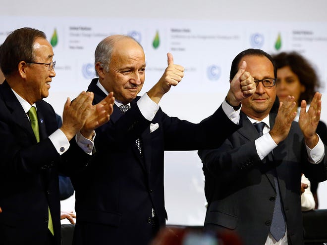 French foreign minister and President of the COP21 Laurent Fabius, center, applauds while United Nations Secretary General Ban Ki-moon, left, and French President Francois Hiollande applaud after the final conference of the COP21, the United Nations conference on climate change.