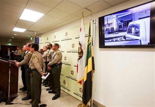 An video released by Los Angeles County Sheriff is shown on a television screen during a news conference about Saturday's fatal shooting of a man in Lynwood, Sunday, Dec. 13, 2015, in Los Angeles. A black man who was fatally shot by Los Angeles deputies kept holding a gun as he lay dying on the ground, authorities said Sunday in response to questions about why they continued to fire on the man after he fell to the pavement. (AP Photo/Ringo H.W. Chiu)