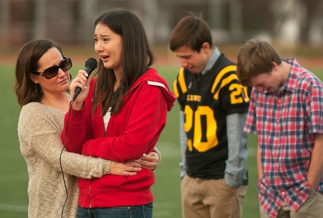 Lori Kim (left) comforts her daughter, Natalie, as she chokes back tears to thank Central Bucks West High School students for turning out to a memorial service honoring her brother Steven at the football stadium Monday, Dec. 14, 2015, in Doylestown. Steven Kim, 14, was struck by a car and killed Saturday night while skateboarding at South Easton and Turk roads in Doylestown Township.