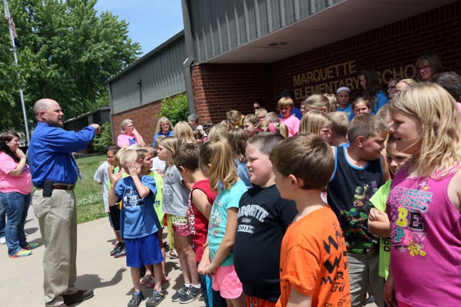 Marquette Elementary School Principal Darryl Talbott directs students into place for a school picture outside the building on May 20, 2014, the final day of school.