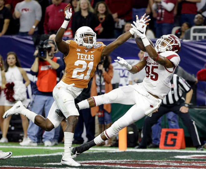 Arkansas's Demetrius Wilson catches a touchdown pass in front of Texas's Duke Thomas (21) during the 2014 Texas Bowl in Houston. There are 41 bowl games between Saturday and Jan. 11.