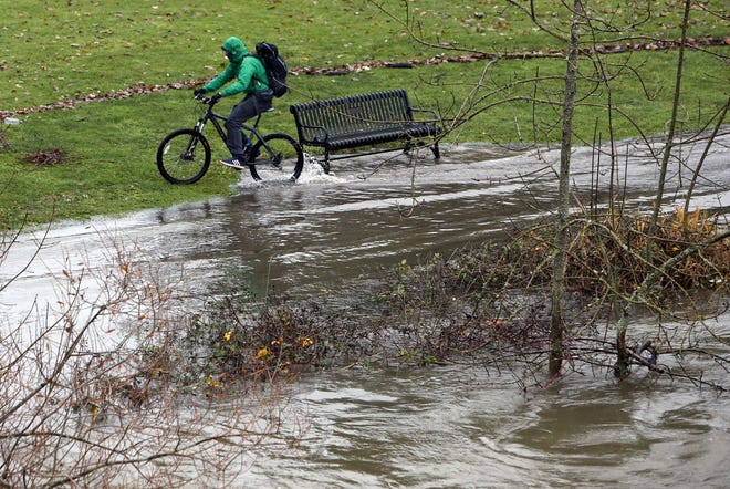 A cyclist exits water covering the bike path along the the rain-swollen Willamette River at Alton Baker Park in Eugene on Monday, December 14, 2015. (Andy Nelson/The Register-Guard)