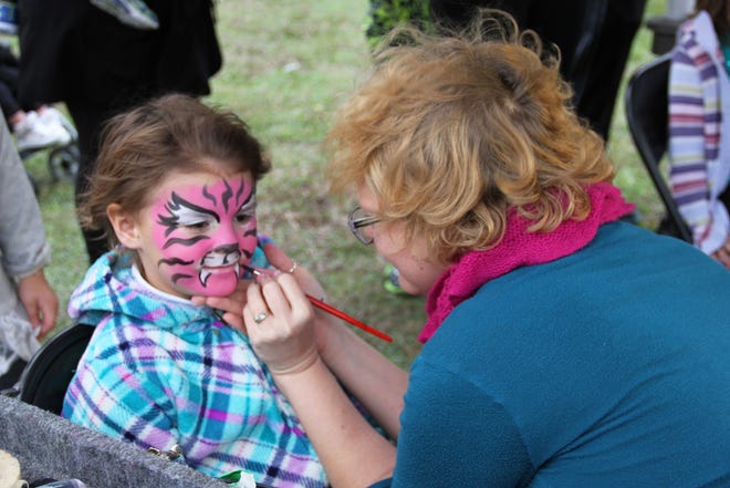 Kristin from Fun Faces paints another whisker on Arabella for "Dashing Through the Grove" at Patriots' Grove on NAS Jacksonville, Dec. 4.