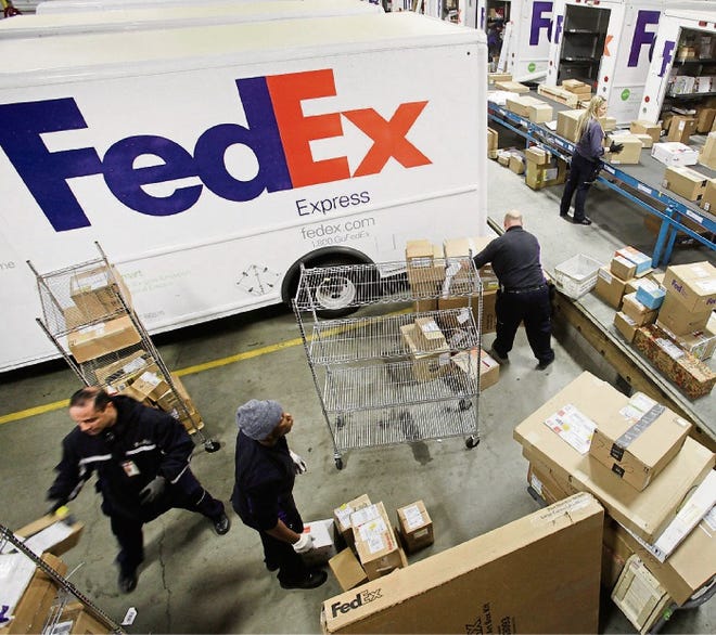 Employees pull boxes from a conveyor belt and fill trucks for deliveries at a FedEx sorting facility in the Bronx borough of New York. FedEx expects holiday shipments to rise 12.4 percent this year.