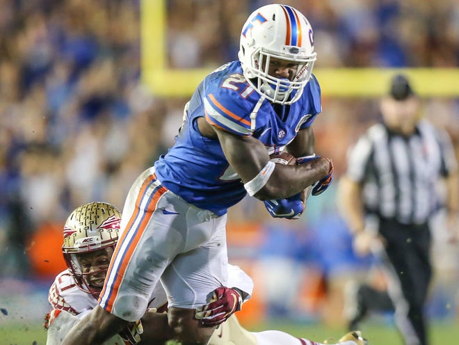 Florida Gators running back Kelvin Taylor (21) is tackled by Florida State Seminoles defensive back Marquez White (27) during the first half of NCAA football action at Ben Hill Griffin Stadium in Gainesville, Fla., Saturday, Nov. 28, 2015.