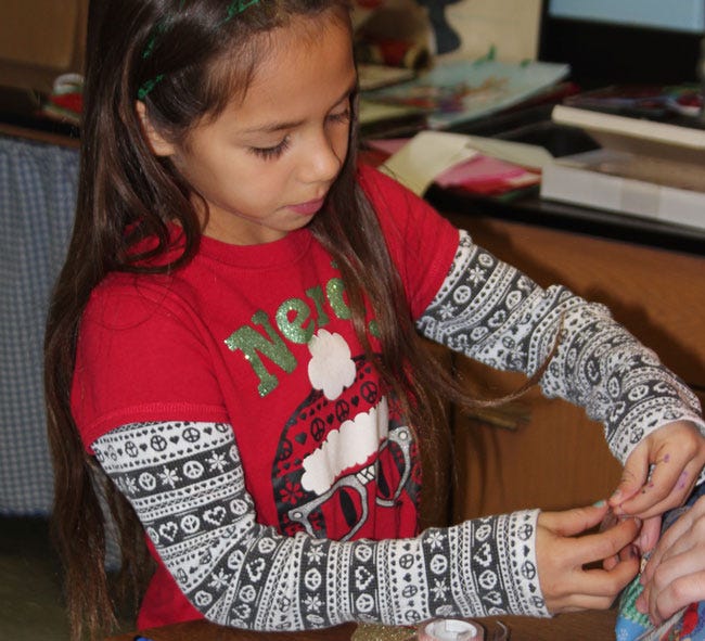 Braylyn Hernandez, a third-grade student at Burr Oak Community Schools, wrapped gifts for her family Thursday at the school's annual holiday “shop.”